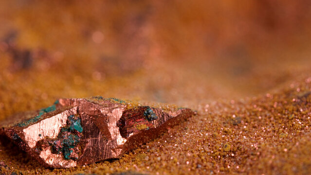 Macro shot of native copper ore nugget on fine copper dust sand with bokeh background