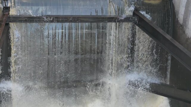 close-up of water cascading through a concrete spillway or dam structure, creating foam and waterfall effect. floodgate metaphor video with sound