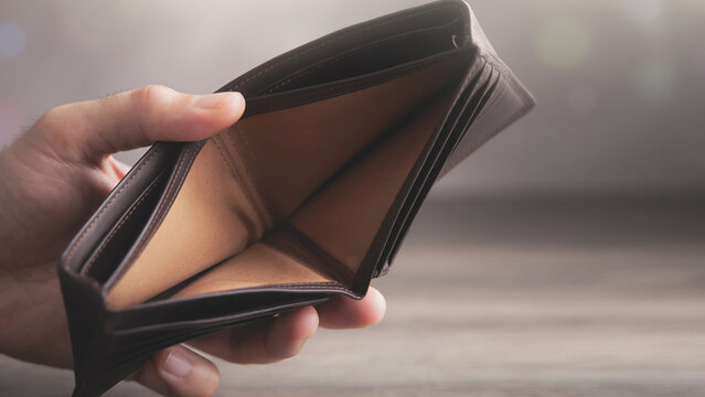 Hand holding an empty brown leather wallet isolated on white background, financial crisis and bankruptcy concept