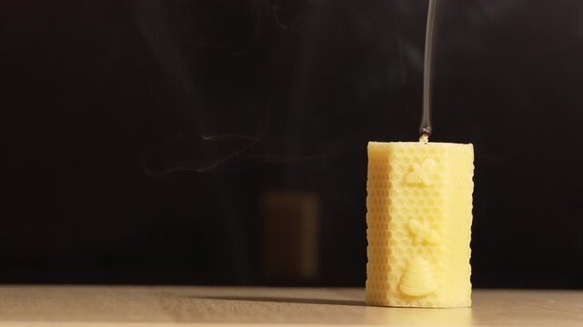 Extinguished Beeswax Honeycomb Candle with Graceful Smoke Trails on a Dark Background with Copy Space