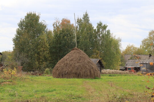 A haystack near old houses on an autumn day