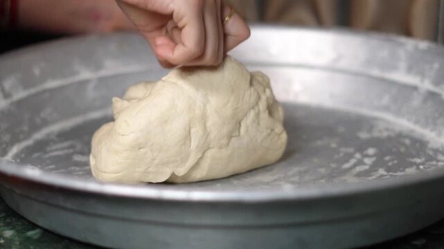 Close Up of Indian Baker Hand Kneading Soft Wheat Flour Dough in Metal Plate. Female Working with White Raw Dough on Steel Platter for Roti Preparation.