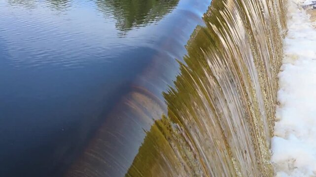 Close-up of water flowing over a low-head dam into a river. Rushing waterfall. video template with sound
