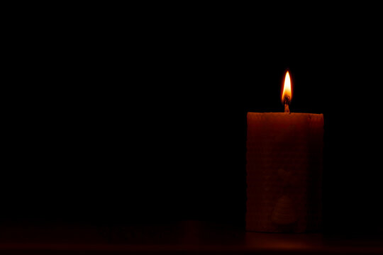Single Lit Artisanal Beeswax Honeycomb Candle Burning on a Dark Background with Copy Space