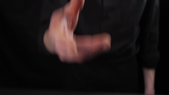 Male chef in a dark shirt tossing and catching a fresh red bell pepper above a wooden cutting board. Professional culinary preparation concept with organic vegetables on a black background