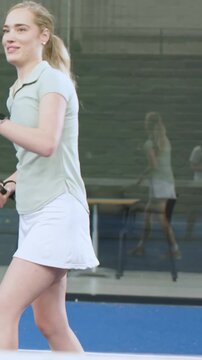 Vertical video: Raising arms, woman in green top walking on court racket ball glass, copy space