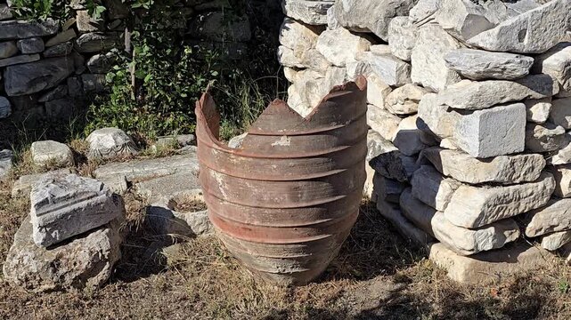 Athens, Greece - 22 June 2026. Broken terracotta storage jar beside stacked stone blocks and carved architectural fragments at Hadrian's Library.