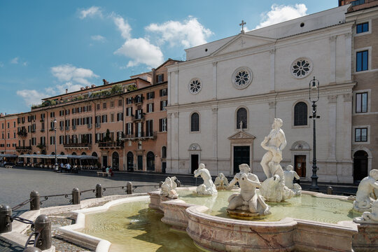 The Fountain of the Moor in Piazza Navona against the white facade of the Church of Nostra Signora del Sacro Cuore on a sunny day in Rome, Italy