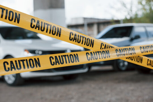 Black and white vehicles. Yellow caution tape near lot at daytime Crime scene