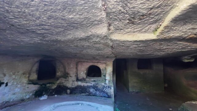 Salina, Malta 06.07.2026 - the interior of an ancient rock-cut catacomb reveals multiple carved burial niches and arched openings within a dimly lit stone chamber, showing centuries of natural weather