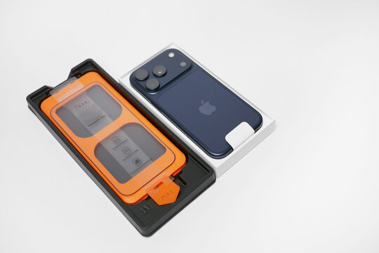 Vienna, Austria - 15 July 2026: New iPhone 17 Pro smartphone with screen protector installation kit isolated on white background - modern technology, packaging and accessory concept.