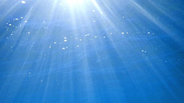 Light filtering down through blue water. Underwater sunlight in deep sea. Light viewed from blue abyss. Underwater sunlight shining deep with ripples on wave surface ocean ray, Under water Slow moti