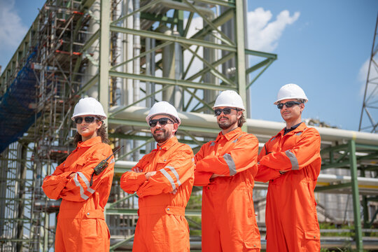 Professional engineering team standing at an oil and gas refinery, highlighting collaboration, safety and industrial operations.