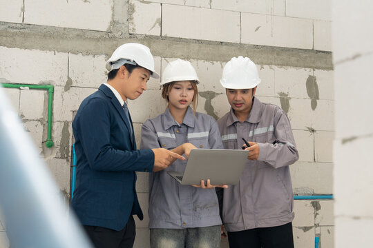 Construction team reviewing project information on a laptop during a site meeting, supporting engineering, collaboration and safety compliance.