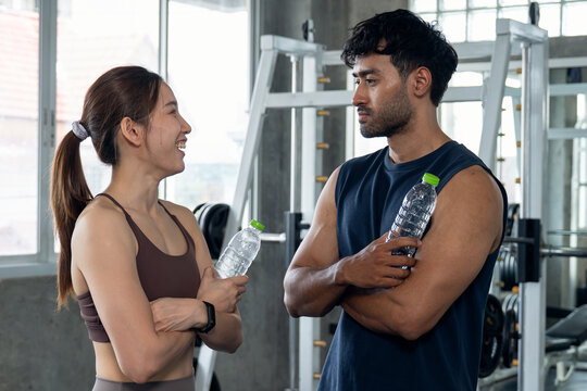 Man and Woman Talking and Smiling While Taking Water Break at Gym.