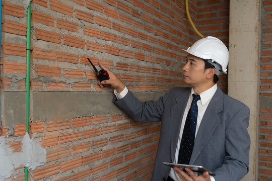 Building inspector reviewing brickwork quality at a construction site, supporting structural inspection, quality control and engineering.