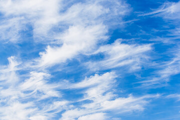 Fototapeta premium Streaks of white clouds trail across a clear blue sky.