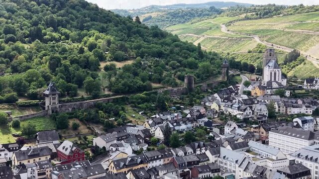 Drone aerial view of the historic town of Oberwesel in the Upper Middle Rhine Valley, Germany. Medieval city walls, defensive towers, traditional half-timbered houses and lush green hills in the UNESC
