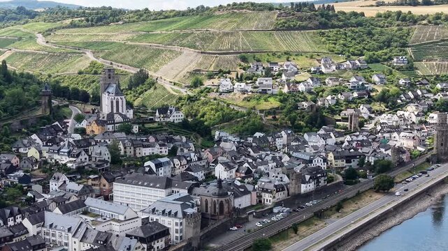 Drone aerial view of the historic town of Oberwesel in the Upper Middle Rhine Valley, Germany. Medieval city walls, defensive towers, traditional half-timbered houses and lush green hills in the UNESC