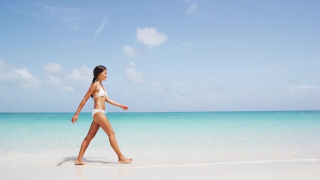 Skincare and body care woman beauty walking on beach wearing bikini. Tranquil, serene and calm skincare or wellness concept with model with perfect skin. Real unretouched woman without any makeup