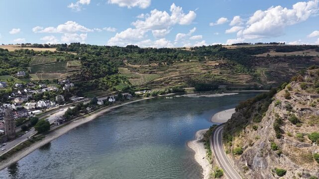 Aerial panorama of terraced vineyards overlooking the Rhine River in the Upper Middle Rhine Valley, Germany. Scenic wine-growing landscape with riverside village, dramatic cumulus clouds, low water le