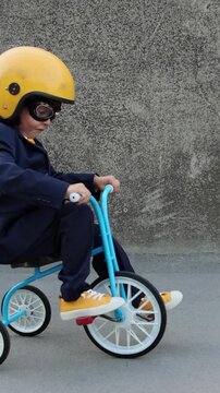 A happy child pretends to be a businessman. Funny kid rides a bike outdoors. A boy has fun during the summer holidays. Back to school, the concept of a business idea. Slow motion, vertical video