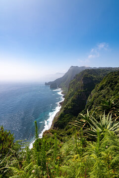 Stunning vertical landscape of the lush green Madeira coastline and blue Atlantic ocean