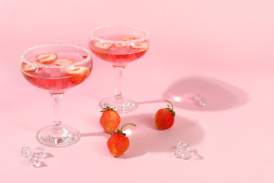 Festive alcoholic cocktail, pink martini in glasses on a bright background with strawberries, summer bar concept, alcoholic drinks at a party, restaurant and cafe advertising, modern still life