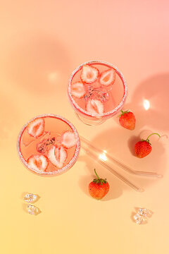 Modern still life with strawberry pink martini, layout, alcoholic cocktail with strawberries on an elegant modern background with long shadows, minimalist concept for bar and holiday party, cafe,