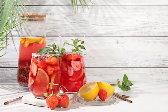 Strawberry Iced Tea or Mint Lemon Cocktail is a refreshing summer drink recipe. Glasses with berry fruit lemonade on a light concrete table, detox diet and weight loss concept, restaurant menu.