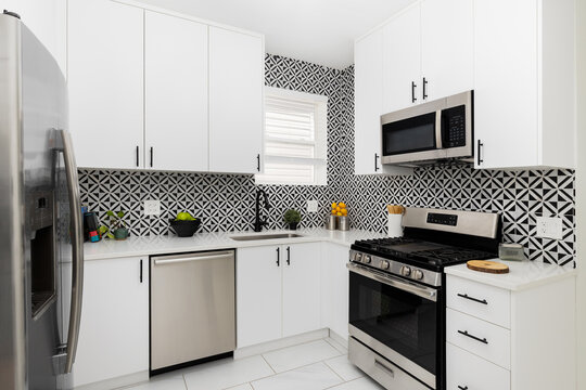A kitchen with white cabinets, diamond black marquina and carrara white marble tile backsplash, and white marble countertop.