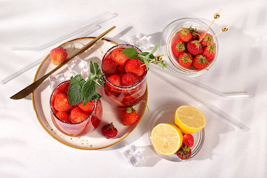 Refreshing summer homemade lemonade cocktail and non-alcoholic mojito, strawberry iced tea with berries, mint and lemon, weight loss concept, detox water with fruit flavor on light background.