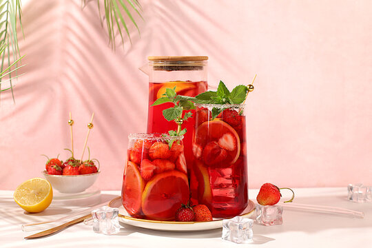 Strawberry Iced Tea or Mint Lemon Cocktail is a refreshing summer drink recipe. Glasses with berry fruit lemonade on a light concrete table, detox diet and weight loss concept, restaurant menu.