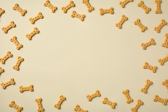 Bone-shaped dog biscuits forming a border frame on a light beige background with copy space in the center.