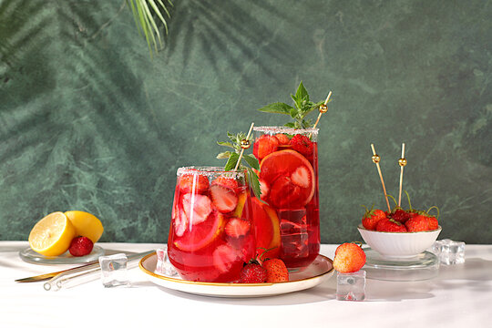Refreshing summer homemade lemonade cocktail and non-alcoholic mojito, strawberry iced tea with berries, mint and lemon, weight loss concept, detox water with fruit flavor on light background.