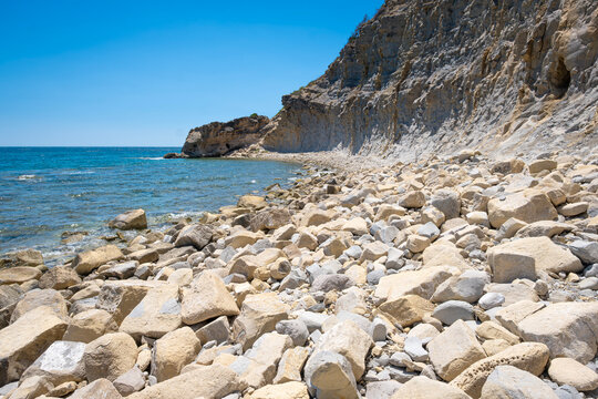 scenic view of the rocky and secluded Cala de la Llobella in Benissa with turquoise Mediterranean waters against dramatic limestone cliffs under a bright blue summer sky