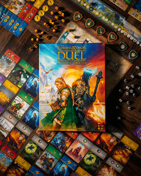 Portrait product photograph of Lord of the Rings Duel for Middle Earth game box and components on wooden table with dramatic lighting designed by Antoine Bauza and Bruno Cathala