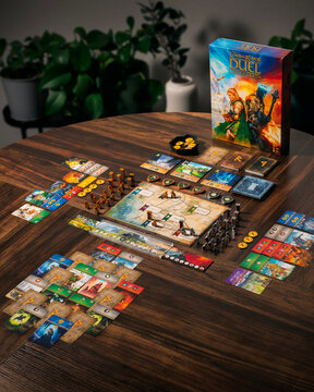 Portrait product photograph of Lord of the Rings Duel for Middle Earth game box and components on wooden table with dramatic lighting designed by Antoine Bauza and Bruno Cathala