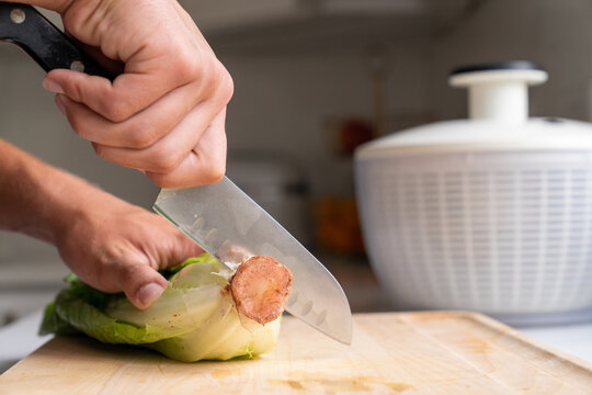 Hand cutting root end off romaine lettuce with knife