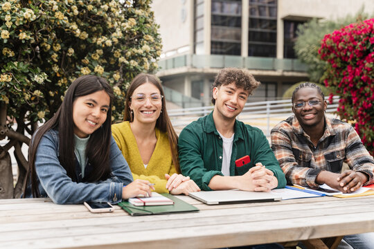 Group of international exchange University Students smiling looking at camera, sitting on table at campus