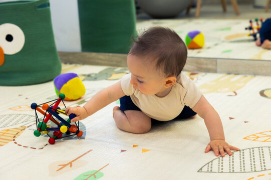 Baby crawling and reaching for colorful sensory toy