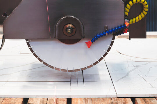 circular saw cuts a marble stone slab with a sharp blade. The rotating blade precisely cuts the tile. Stone industry, tech industrial technology background