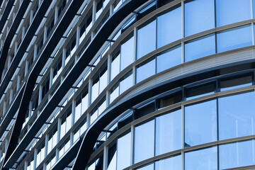 Obraz premium Modern architectural building facade featuring curved glass windows and metal accents, showcasing a contemporary design in an urban environment