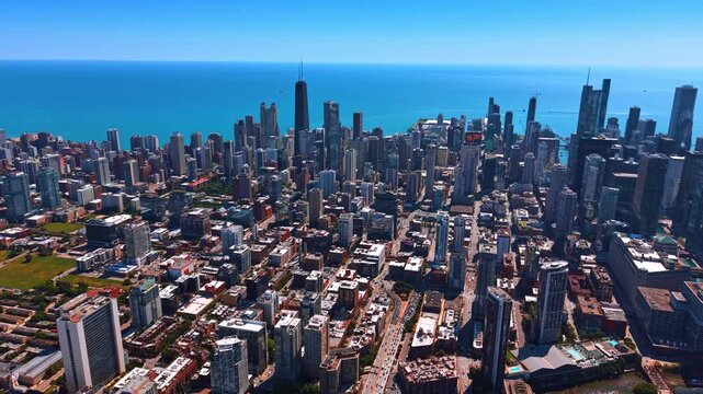 Sunny urban landscape of modern Chicago, Illinois, USA against Lake Michigan. Multiple cars go by the highways of the cityscape.