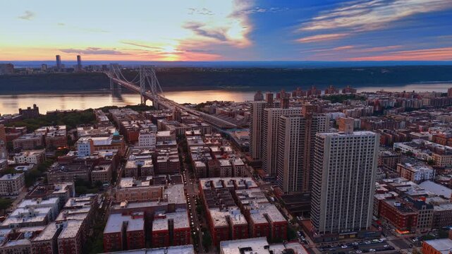 Rising over dense high-rise apartment buildings and residential blocks of Washington Heights and the West Bronx. View on the George Washington Bridge at sunset time.