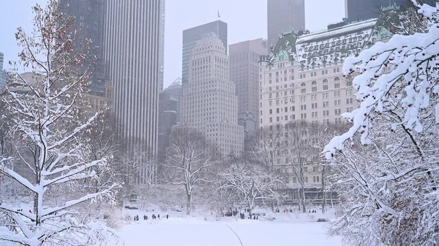 Beautiful snowy winter day in Central Park. People walk by the snow during blizzard.