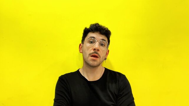 Young man with glasses and mustache turning his head on a yellow background