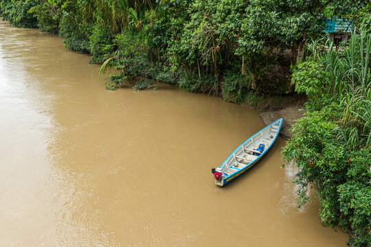 An aerial view of a traditional wooden boat or canoe docked at the port of Chuchumbetza on the Zamora River, an important river transportation hub and a tourist destination in Ecuador's Amazon region