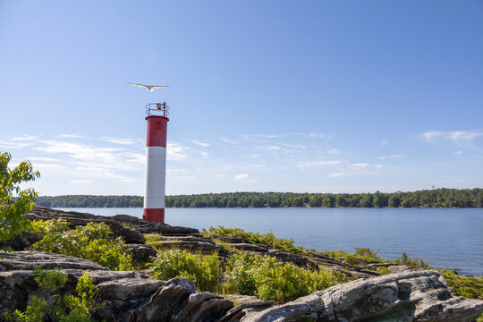 Lighthouse on rocky shoreline overlooking calm waters at Killbear Provincial Park, Ontario.