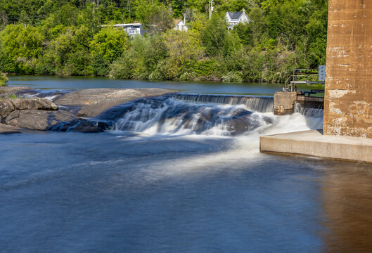 A tranquil small waterfall flows beneath a trestle bridge in Parry Sound, Ontario.